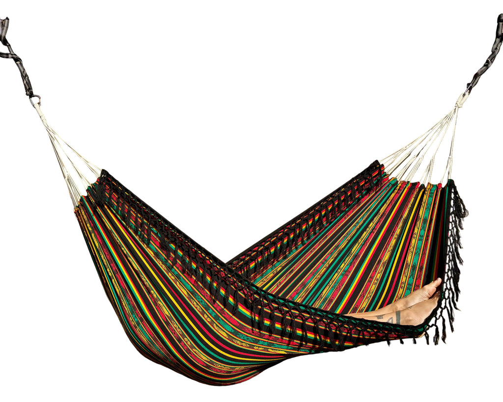 A colorful striped hammock suspended under a wooden pergola, with a person's legs visible resting inside the hammock.